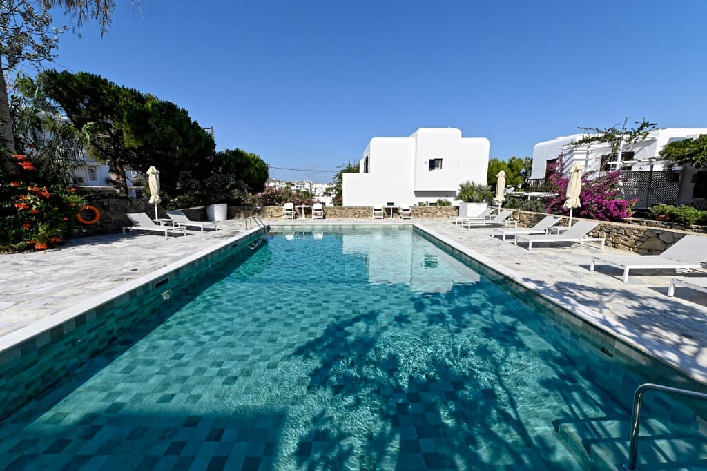 Shared swimming pool at Residence Triantafillidis with lounge chairs and white Cycladic buildings